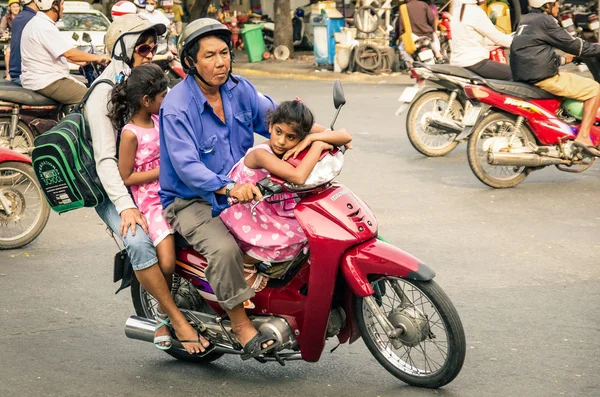 HO CHI MINH CITY, VIETNAM - 6 DE FEBRERO DE 2013: familia completa conduciendo un scooter en el tráfico de la ciudad. Hay aproximadamente 340.000 coches y 3,5 millones de motocicletas en la ciudad . —  Fotos de Stock