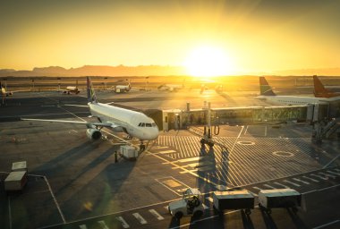Terminal kapısındaki uçak günbatımında modern uluslararası havaalanından kalkmaya hazır.