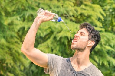 Sportif adam parkta - spor fitness genç mutlu modeli doğada koşu sonra bir mola çalışma eğitimden sonra soğuk suyla ferahlatıcı