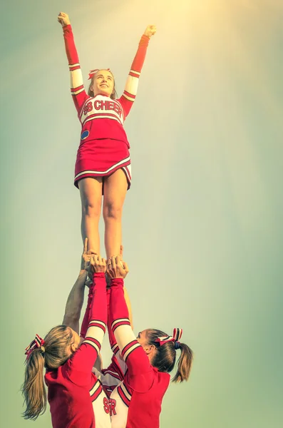 Cheerleaders in action on a vintage filtered look - Concept of unity and team sport - Training at college high school with young women teenagers — стоковое фото