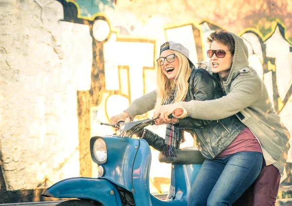 Jonge paar liefhebbers haviing plezier op een vintage scooter bromfiets - knappe man in speelse houding met zijn mooie vriendin - begin van een verhaal van de liefde op een warme zonnige winterdag — Stockfoto