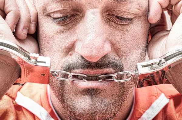 Sad depressed detained man with handcuffs in prison - Handcuffed inmate prisoner in jail with orange clothes - Crispy desaturated dramatic filtered look - Dead man walking concept and death penalty — Stock Photo, Image