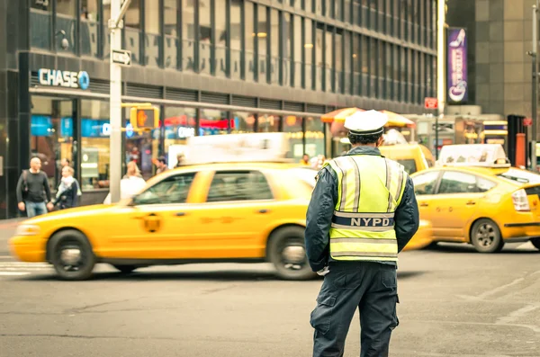 New York City - 22 December, 2013: oidentifierade Nypd officer på gatorna i Manhattan med gula taxibilar. Grundades 1845 och är Nypd största kommunala polismyndighet i USA — Stockfoto