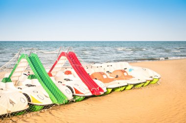 Paddle boat at italian beach - Beginning of summer season 2015 in Rimini Italy - Summer international tourism destination - Postcard for hotel vacation catalogue clipart