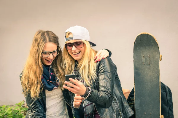 Best friends enjoying time together outdoors with smartphone - Concept of new trends and technology with hipster girlfriends having fun in urban city area - Alternative four seasons fashion clothes — Stock Photo, Image