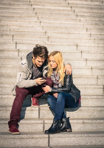 Hipster pareja en el amor divertirse con el teléfono inteligente - Concepto moderno de conexión en una relación junto con la tecnología de telefonía móvil - Ciudad estilo de vida urbano que representa la relación de la vida cotidiana — Foto de Stock