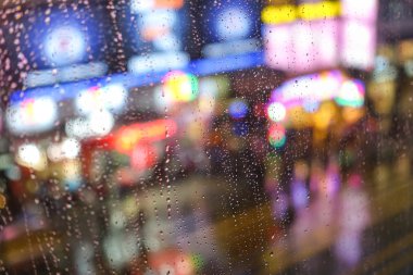 Pencere cam - odak alan sığ derinliği nedeniyle birkaç damla yağmur arkasında Nathanroad Hong Kong, ufuk ışık bokeh ile duygusal arka plan damla