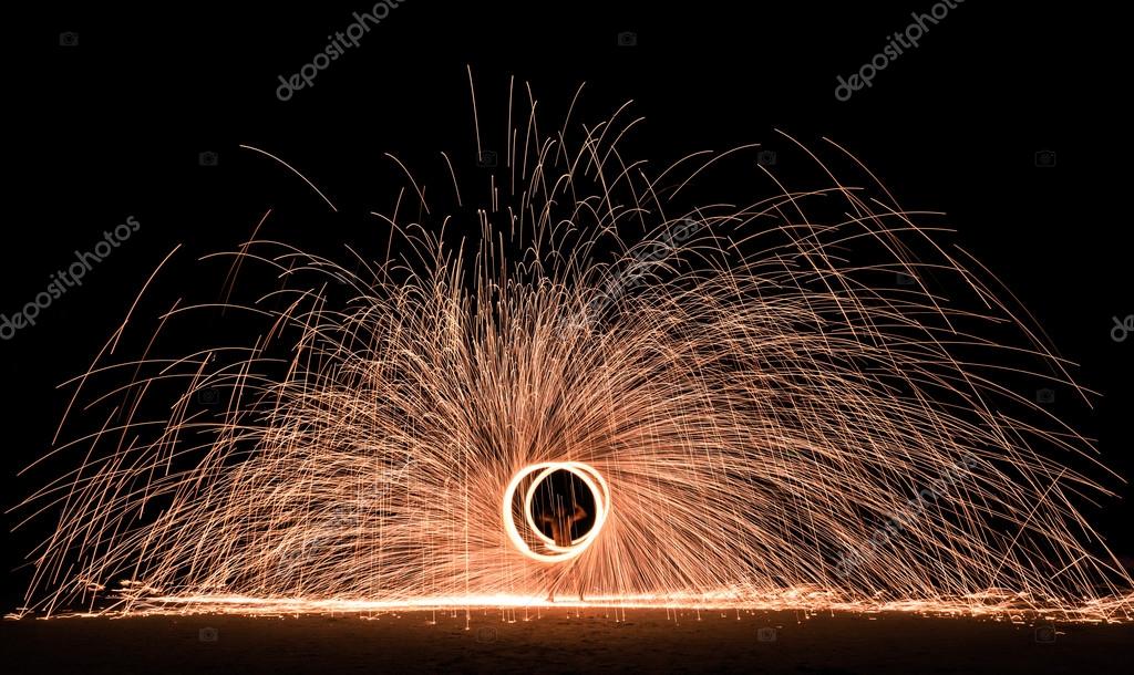 Firestarter performing amazing fire show with sparkles in the night Full moon party