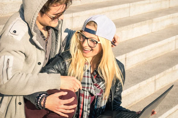 Casal de jovens hipster com laptop de computador em localização urbana ao ar livre - Conceito de interação e diversão com novas tendências e tecnologia - Conexão sem fio e internet na web redes sociais — Fotografia de Stock