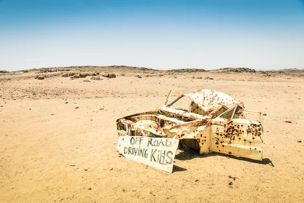 Car wreck in the namibian desert - Danger sign about driving off roads — Stock Photo, Image