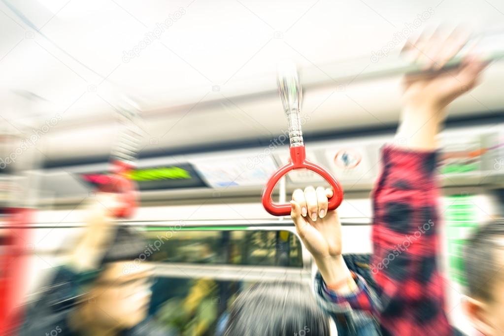 Concept of metropolitan transportation during rush hour - Hong Kong underground with radial zoom defocusing and vintage filtered look - Focus on the hand holding train handle during subway trip