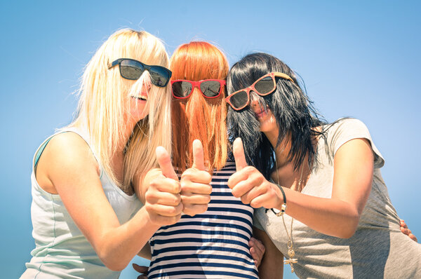 Group of young girlfriends with focus on colored funny hair and sunglasses - Concept of friendship and fun in the summer expressing positivity with thumbs up - Best friends sharing happiness together