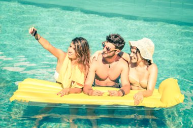 Arkadaşlarım sarı sonraki - yaz dostluk kavramı ile yeni trendler ve teknoloji - erkek ve kız arkadaşları ile pozlanmış bir vintage smartphone ile Yüzme havuzunda selfie almayı göz filtre