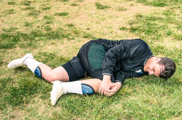 Soccer player injured during amateur football match - Concept of sport failure and physical accident — Stock Photo, Image