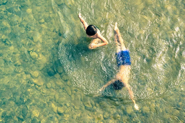 Unbekannte Kinder schwimmen und amüsieren sich im nam song fluss in vang vieng - realer alltag der kinder in laos pdr ländliche region - echte glückliche freizeitkultur und tiefe naturverbundenheit — Stockfoto