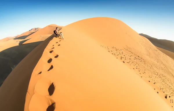 Hombre solitario sentado en la arena en la Duna 45 en Sossusvlei - Concepto de vagabundeo en el famoso desierto namibio - Viaje de aventura a las maravillas africanas en Namibia - Composición con distorsión de lentes de ojo de pez — Foto de Stock