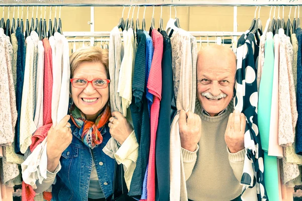 Pareja mayor juguetona en el débil mercado de pulgas - Concepto de ancianos activos con hombres y mujeres maduros divirtiéndose y comprando en el casco antiguo - Felices momentos de jubilación en una cálida mirada nostálgica vintage — Foto de Stock