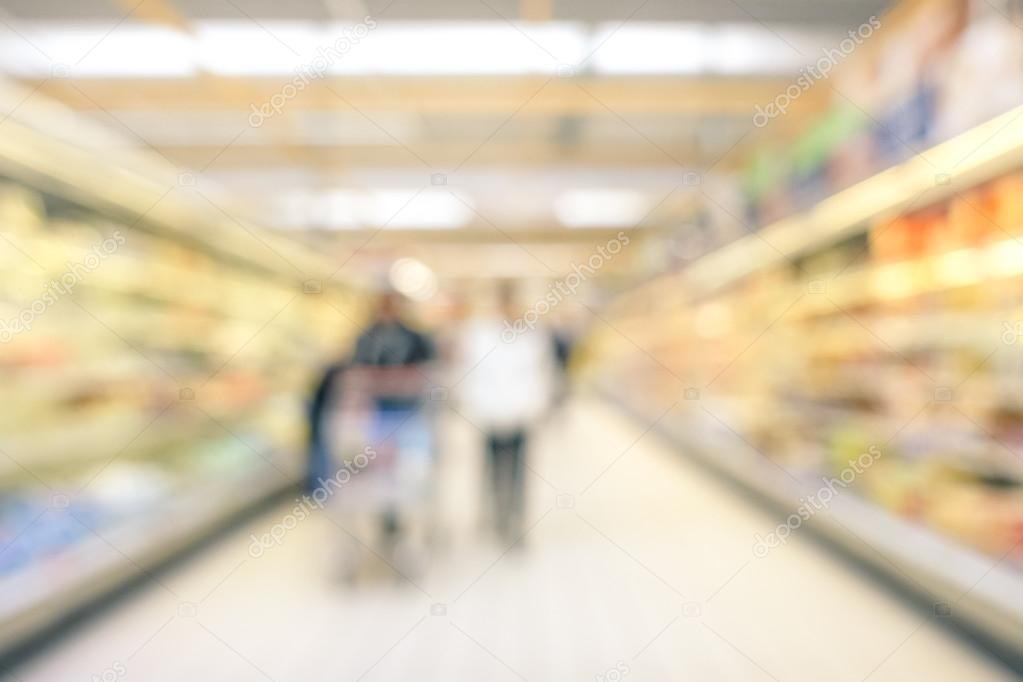 Blurred defocused background of generic supermarket lane- Concept of consumerism during a period of economic crisis - Neutral blur of couple of people in empty corridor at grocery commercial center