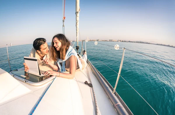 Pareja joven enamorada en barco de vela divirtiéndose con la tableta - Feliz estilo de vida de lujo en velero yate - Interacción tecnológica con conexión wifi por satélite - horizonte redondo de la distorsión de la lente de ojo de pez — Foto de Stock