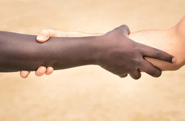 Black and white hands in modern handshake to show each other friendship and respect - Helping and respecting each other against racism - Slightly crispy detailed filtered look on defocused background — Stock Photo, Image