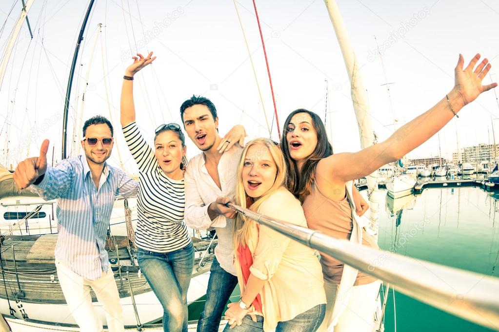 Best friends using selfie stick taking pic on exclusive luxury sailing boat - Concept of friendship and travel with young people and new technology  trends - Bright nostalgic desaturated color tones