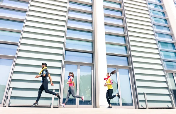 Gruppo di giovani che corrono nell'area urbana moderna - Ragazze in forma che corrono con allenatore di sesso maschile in città - Concetto sportivo con gli amici che fanno jogging nel centro commerciale in una giornata soleggiata e luminosa — Foto Stock