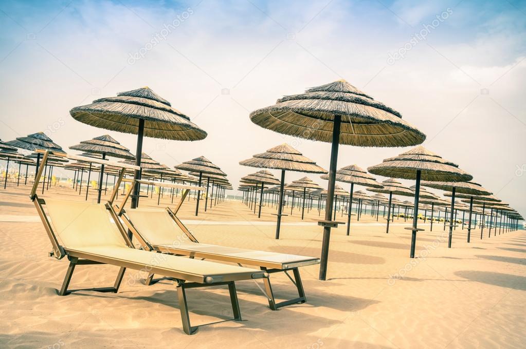 Straw umbrellas and sunbeds at Rimini beach in Italy - Top destination in Emilia Romagna adriatic coast - Vintage filtered look of the world famous italian Riviera with tilted horizon composition