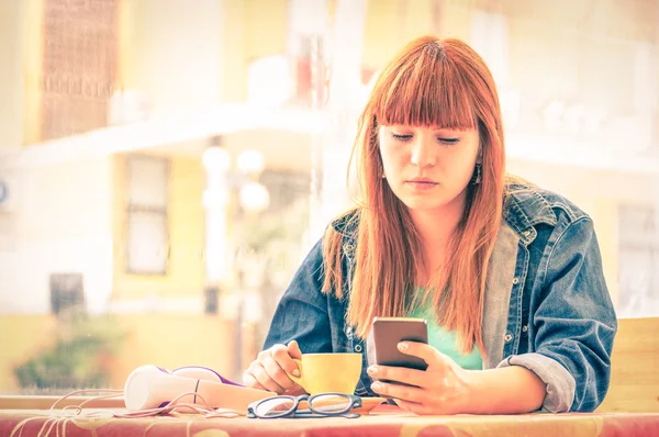 Vintage gefiltertes Porträt einer ernsthaft nachdenklichen jungen Frau mit Smartphone - Hipster-Mädchen benutzt Handy beim Kaffeetrinken - Konzept menschlicher Emotionen - weicher Fokus auf traurigem besorgtem Gesicht — Stockfoto