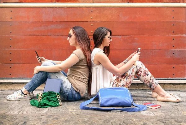 Hipster couple of girlfriends in disinterest moment with mobile smart phones - Concept of relationship apathy sadness and isolation using new technologies - Female friends with smartphones addiction — Stock Photo, Image