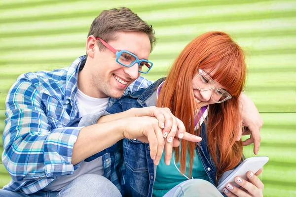 Joyeux jeune couple qui s'amuse avec son smartphone à l'emplacement vintage grunge - Concept d'amitié avec les meilleurs amis hipster interagissant avec les nouvelles technologies - Début des moments d'une histoire d'amour — Photo