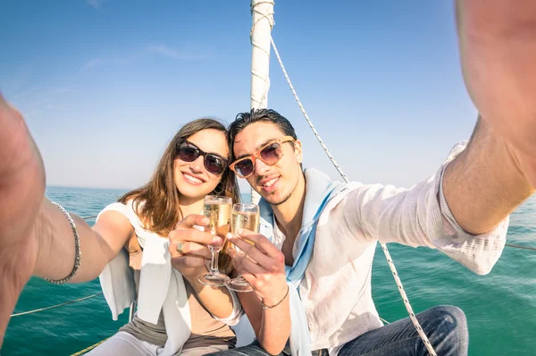 Young couple in love taking selfie on sailing boat cheering with champagne wine - Happy jubilee party cruise travel on luxury sailboat with boyfriend and girlfriend - Bright sunny afternoon color tone — Stock Photo, Image