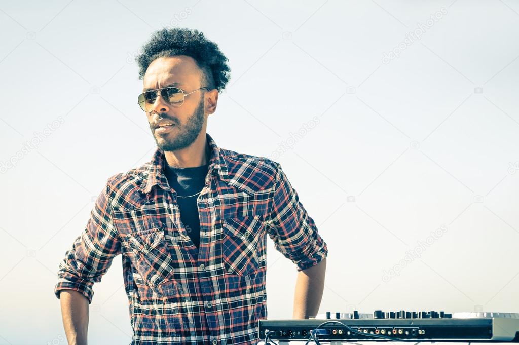Afro american model artist ready to perform at dj console during spring break festival - Hipster funky disc jockey at summer beach party - Male trendy person with sunglasses at disco rave event