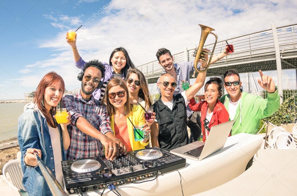 Funky hipster people taking selfie and having fun together at beach rave afterhour party - Summer festival moments with young disc jockey happy friends - Dj playing trendy sound at open air disco club