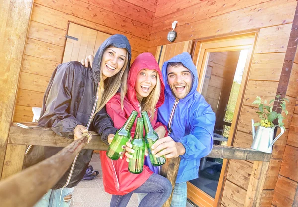Beste vrienden nemen gekanteld selfie op camping bungalow met zon na de regen - jeugd en vrijheid concept buiten in het najaar van vakanties - jonge mensen met plezier en de juichende met flessenbier — Stockfoto