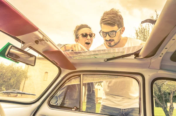 Pareja de amantes mirando un mapa durante las vacaciones de luna de miel - Estilo de vida vintage viajando por todo el mundo con viejo coche clásico retro - Jóvenes disfrutando juntos momentos felices de la vida —  Fotos de Stock