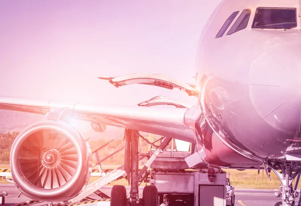 Detail of airplane at terminal gate before takeoff - Travel concept and wander around the world in international airport at sunset - Vintage marsala filtered look with sunshine halo — Stock Photo, Image