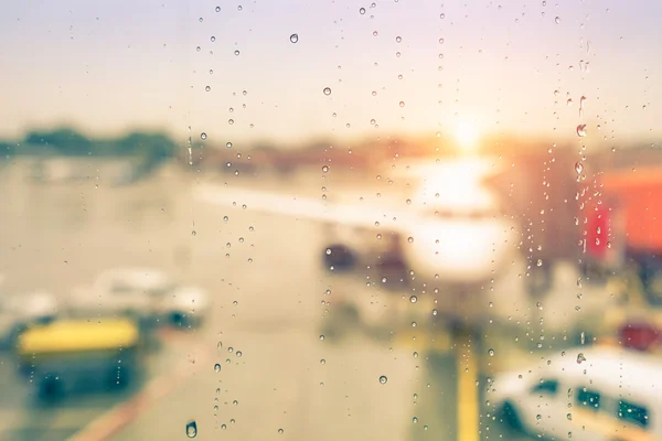 Bokeh desenfocado abstracto de avión en la puerta del aeropuerto con el sol saliendo después de la lluvia - Concepto de viaje moderno y estilo de vida errante al atardecer - Enfoque en las gotas de lluvia con aspecto cálido filtrado vintage — Foto de Stock