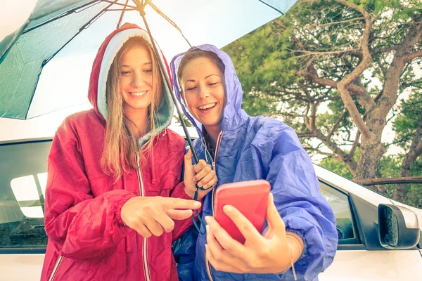 女性の親友 - 一緒に楽しんで若いガール フレンドと車旅 - 雨の後出てくる太陽ビンテージ バックライトと太陽のハローのためにソフト フォーカス フィルターをスマート フォンで楽しんで — ストック写真