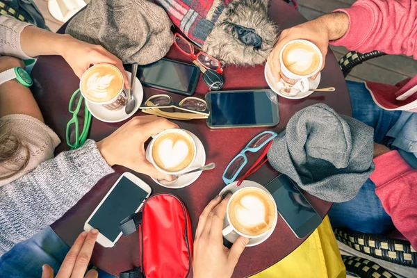 Freundeskreis trinkt Cappuccino in Kaffeebar-Restaurants - Menschen greifen mit Smartphones nach oben - Technologiekonzept mit süchtigen Männern und Frauen - weicher Vintage-Filter Stockfoto