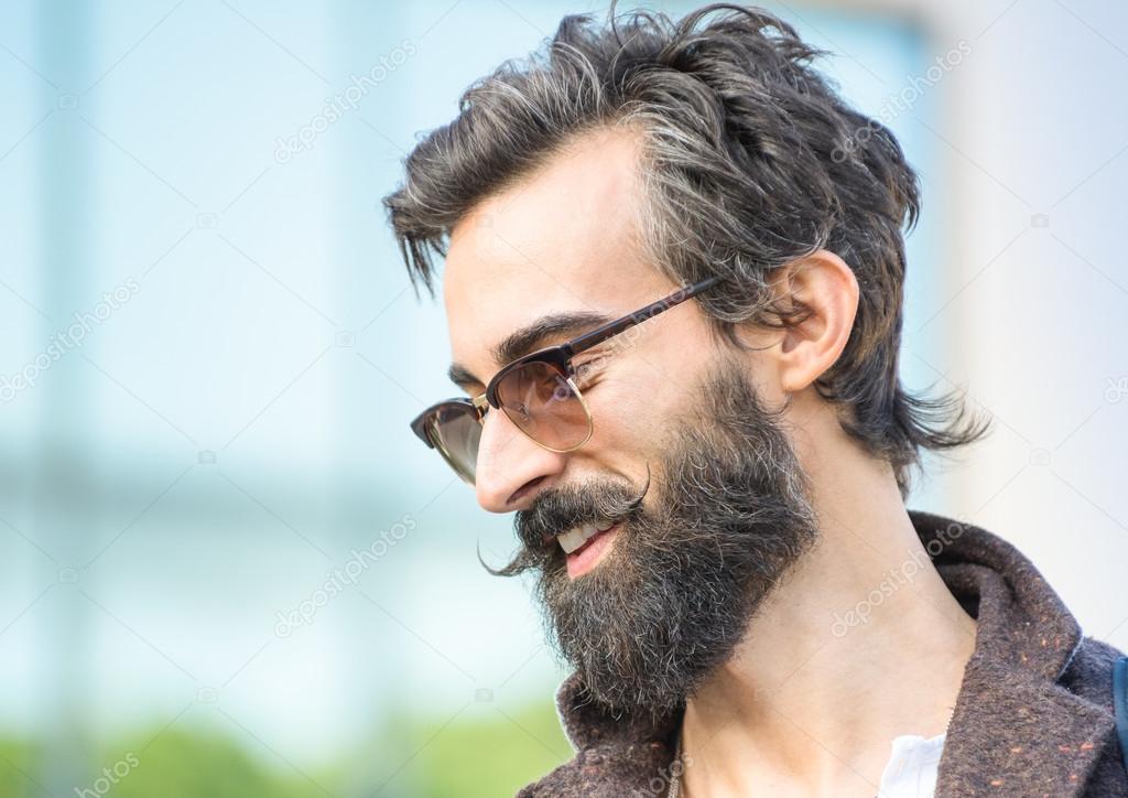 Portrait of hipster guy with confident face expression - Autumn fashion male model posing outdoors - Young man with beard and alternative mustache - Soft retro filter and shallow depth of field