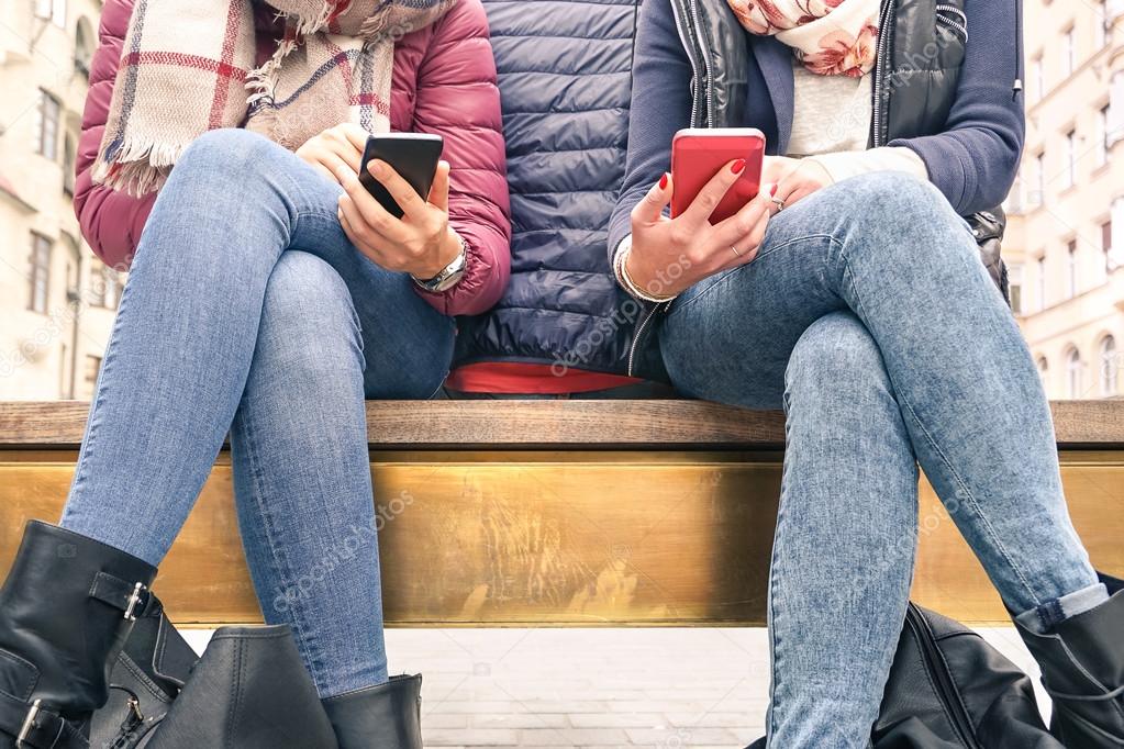Close up of couple of girlfriends in disinterest moment with mobile smart phones - Concept of relationship apathy sadness and isolation using new technology - Female friends with smartphone addiction