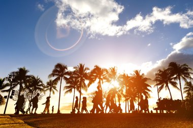 Kalakawa Ave - açık yürüyüş sokak mesire Waikiki Beach Honolulu Hawaii - gelişmiş güneş ışığı mercek parlaması kompozisyon parçası olarak sıcak filtresiyle silüeti gün batımında üzerinde yürüyen insanlar kalabalık