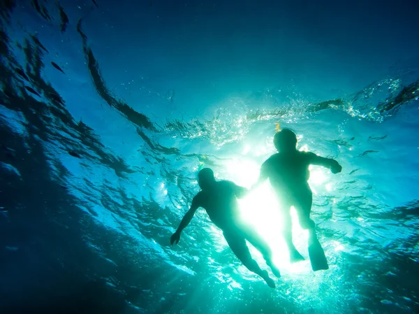 Silhouette of senior couple swimming together in tropical sea - Snorkeling tour in exotic scenarios - Concept of active elderly and fun around the world - Soft focus due to backlight and water density — Stock Photo, Image