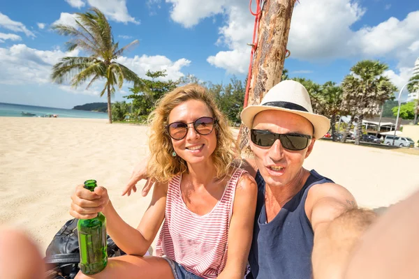 Pareja feliz tomando selfie en la playa - Concepto de estilo de vida de viaje con los jóvenes divirtiéndose juntos - Viaje a Tailandia en la zona costera de Karon en la isla de Phuket - Tonos cálidos de color y horizonte inclinado —  Fotos de Stock