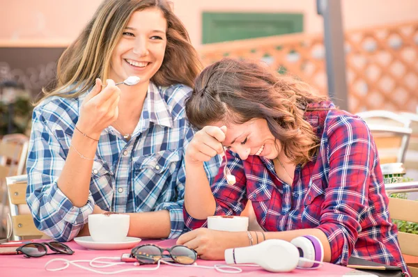 Happy couple of girlfriends drinking cappuccino and laughing together - Happiness concept with young women talking and having fun at coffee bar - Warm vintage filter with focus on girl face at right — Stock Photo, Image