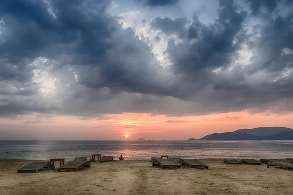 Vietnam, Nha Trang, Sandy beach, empty sunbeds, the calm sea, the sunrise, a lone man is looking into the distance — Stock Photo, Image