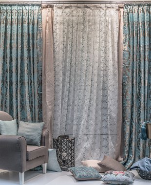 Turkuaz ve bej tonlarında rahat bir iç. Kombine perdeler, şeffaf tül, yastıklar ve şık bir klasik koltuk.
