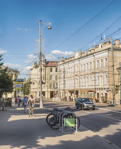 Moscow. July 20, 2014. The bicycle parking, the cyclist and people hurry about their business on the Volkhonka street.