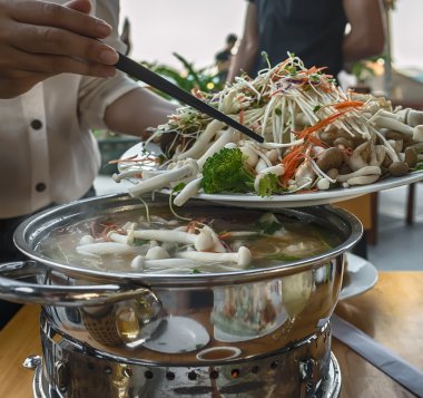 Bir kafe ve restoran yemek masası üzerinde Vietnamca, Asya yemekleri pişirme. Yangında büyük bir tavada mantar ve deniz ürünleri pişirilir.