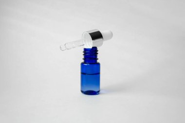 Blue glass bottle with pipette dispenser on white background. Collagen, anti-aging skin care products. Skin moisturizer with hyaluronic acid. clipart